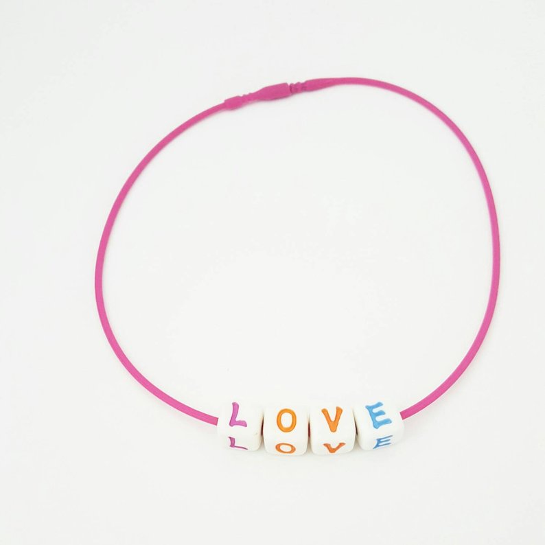 Pink choker necklace with blocks spelling LOVE.